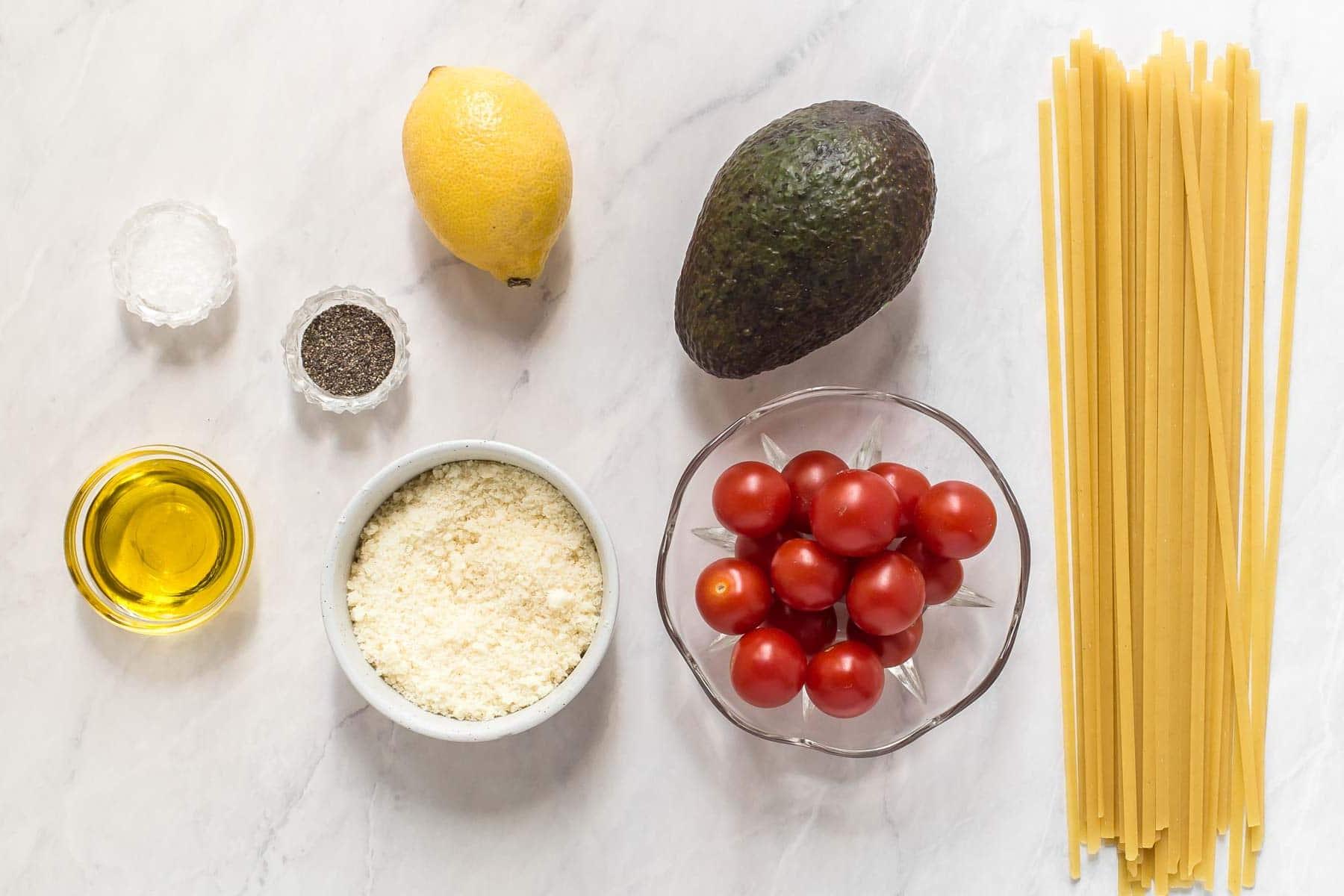 Ingredients for avocado pasta sauce on white table.