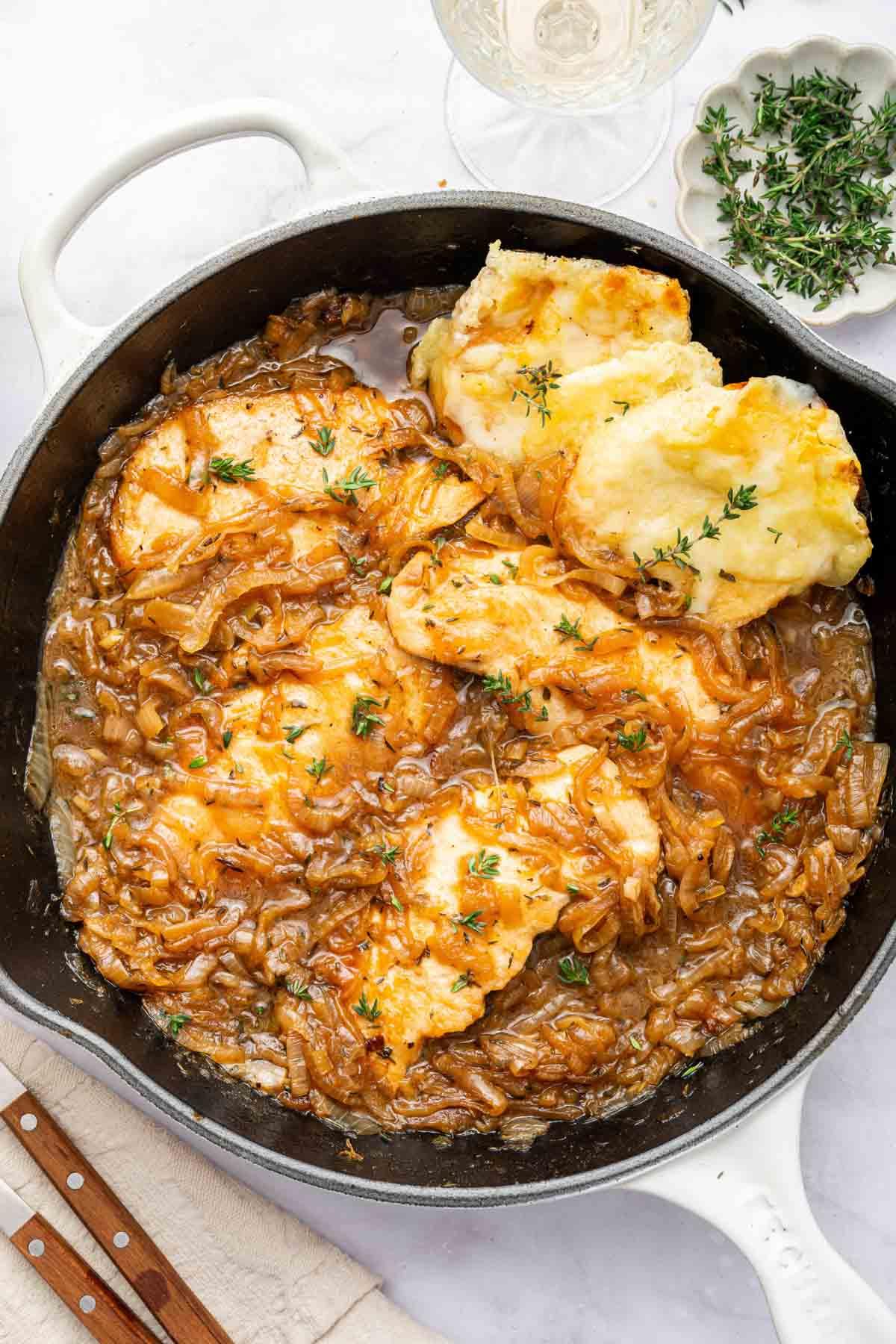 Ricetta del Pollo alla Cipolla Francese 10 Padella nera con Pollo alla Francese e pane tostato a lato, pronto per essere servito.