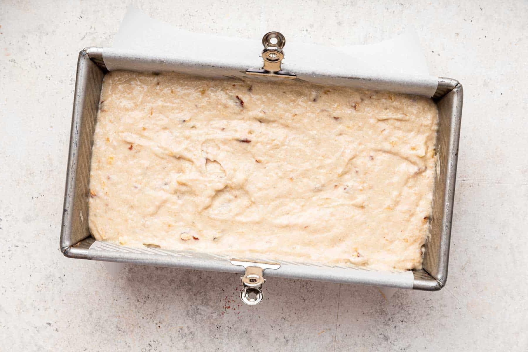 Pane alle banane senza uova 10 Impasto giallo pallido in uno stampo per pane.