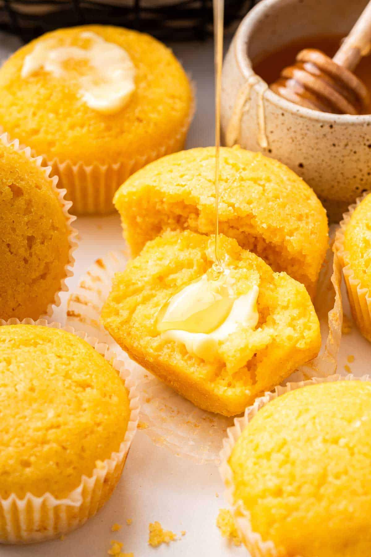 Ricetta Muffin al Mais 10 Muffin di mais tagliato a metà con burro che si scioglie sopra.