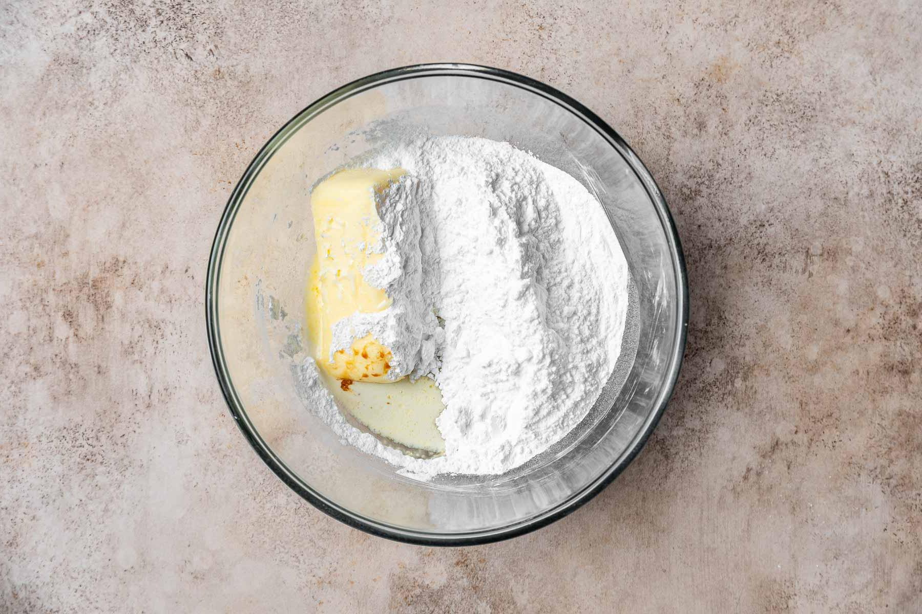 Burro, zucchero a velo e crema in una ciotola trasparente.