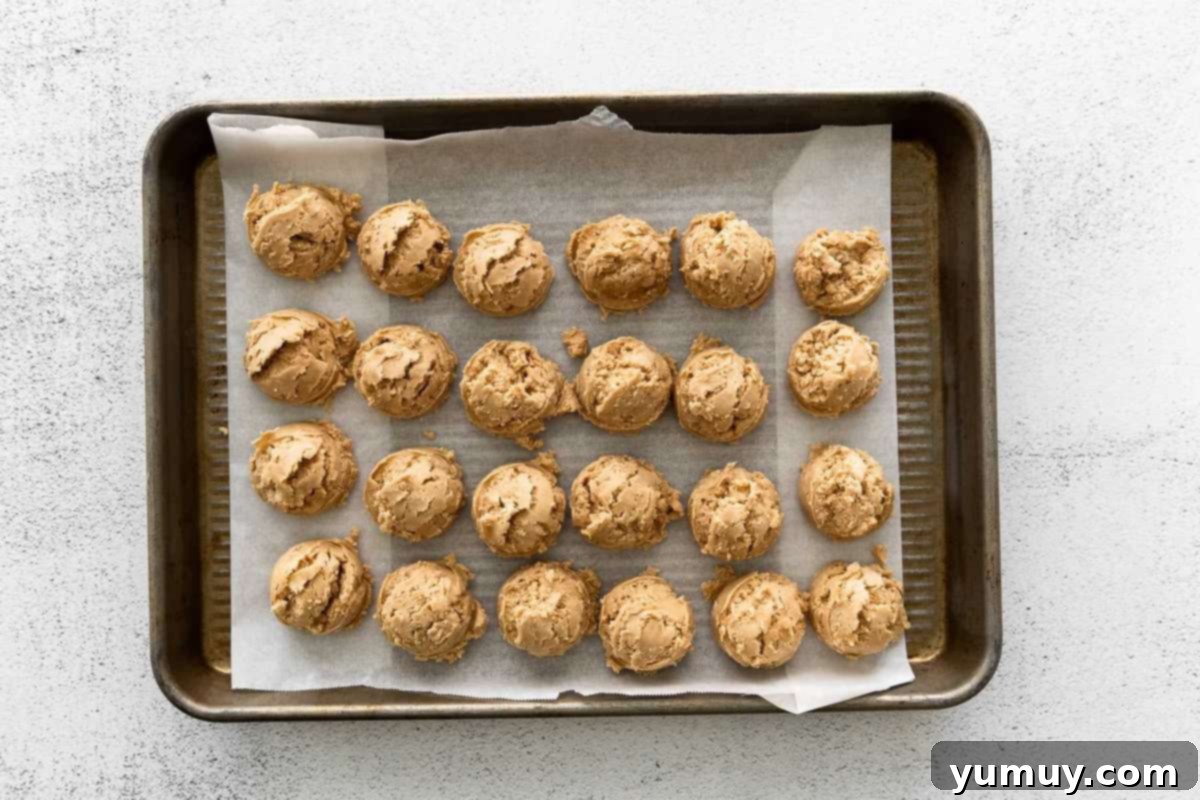 Peanut butter balls lined up on a tray, ready for chilling.