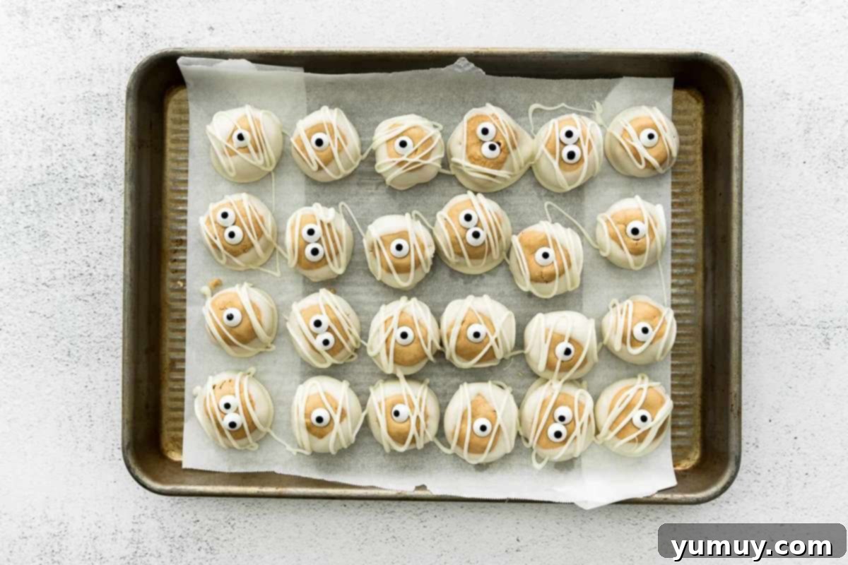 Halloween Buckeyes decorated like mummies with candy eyes and white chocolate drizzles.