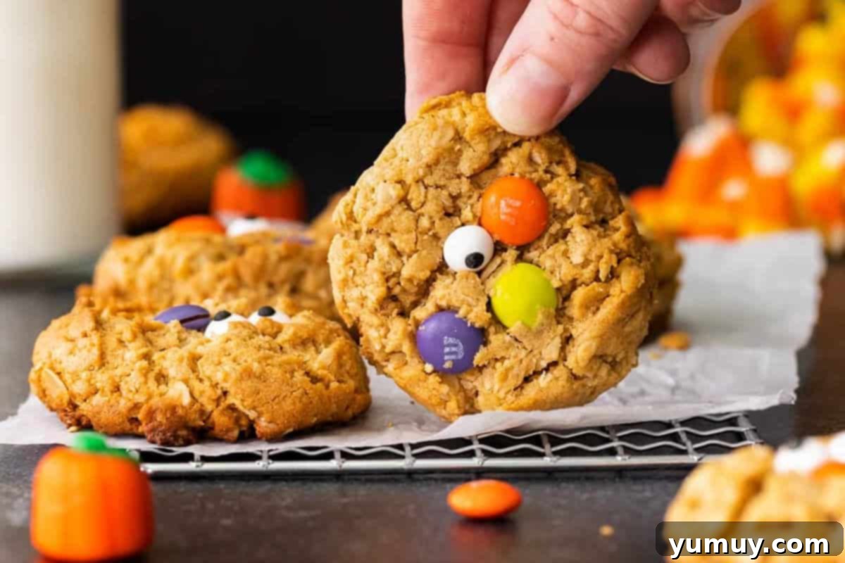 Spooktacular Monster Cookies 3 Hand holding up a halloween monster cookie to show the colorful candies on top.