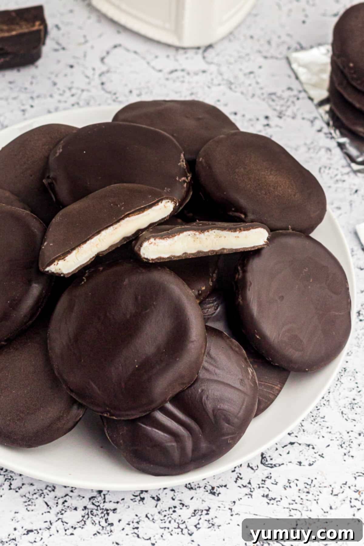 Homemade chocolate peppermint patties arranged beautifully on a white plate, showcasing their smooth chocolate coating and festive appeal.