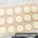 Uncoated peppermint patties neatly arranged on a baking sheet lined with parchment paper, ready for drying.