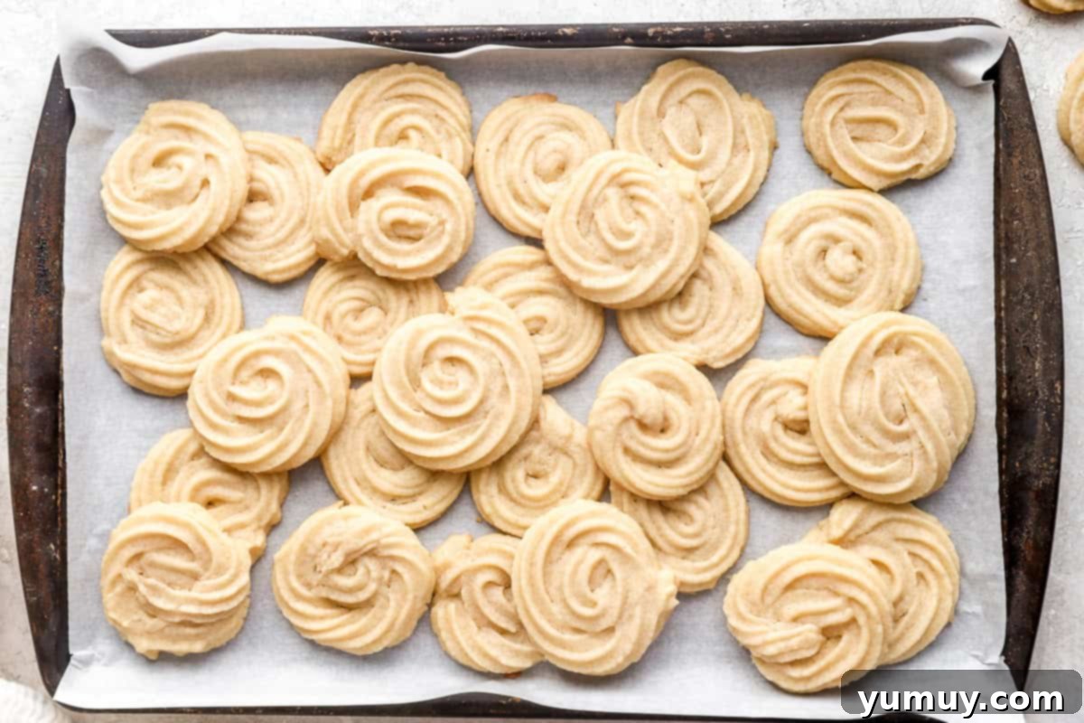 Pure Butter Delights 14 A baking tray filled with freshly baked, perfectly golden-brown butter cookies, cooling slightly.