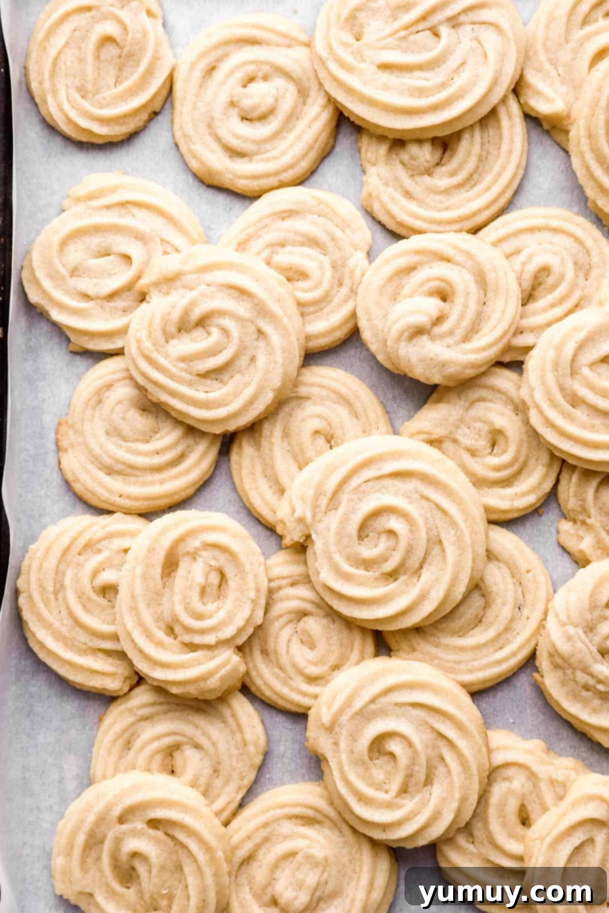 Pure Butter Delights 3 Butter cookies piled up on a baking sheet, showing their golden edges and soft centers.