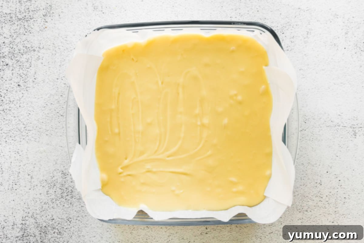 Haunted Fudge Delights 11 The smooth white chocolate fudge mixture has been poured into the parchment-lined square baking dish and spread evenly.
