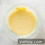 Haunted Fudge Delights 6 Step-by-step photos for how to make Halloween fudge, showing melted white chocolate in a glass bowl.