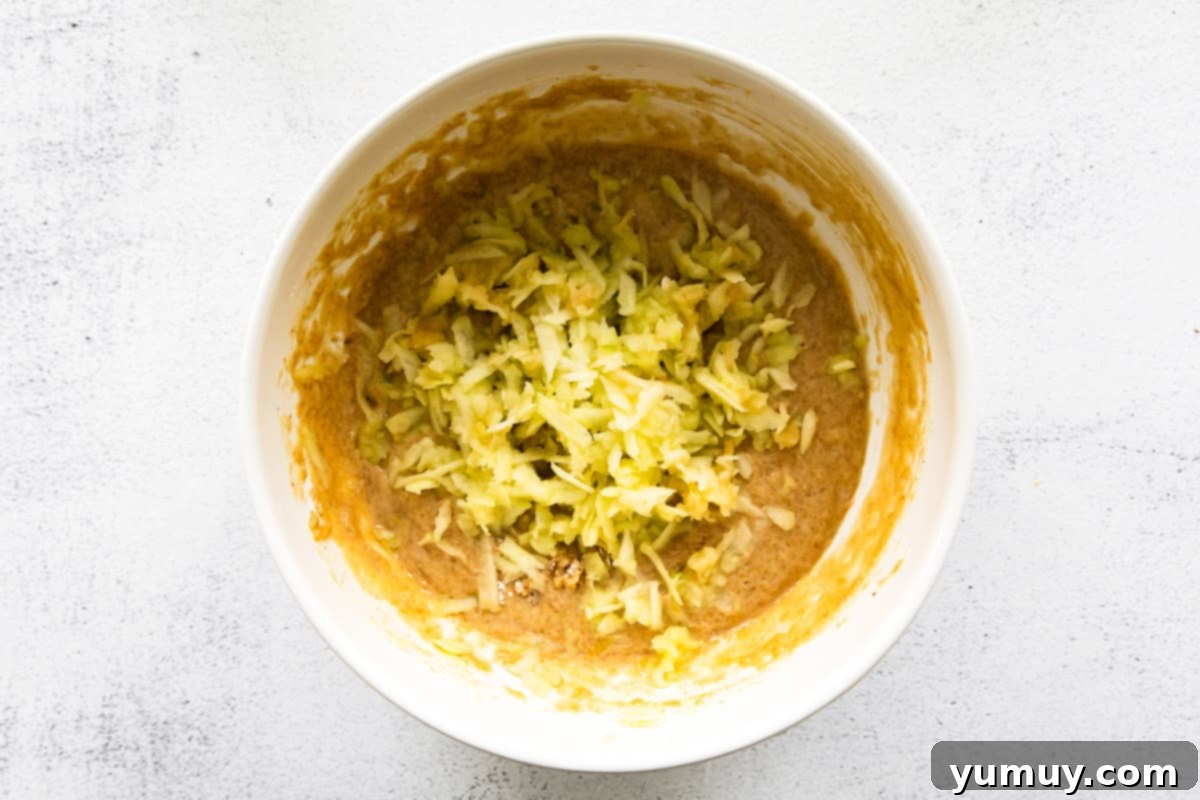 apple cupcake batter with shredded apple in a white bowl