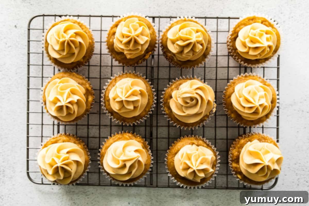 overhead image of 12 apple cupcakes topped with caramel frosting on a cooling rack
