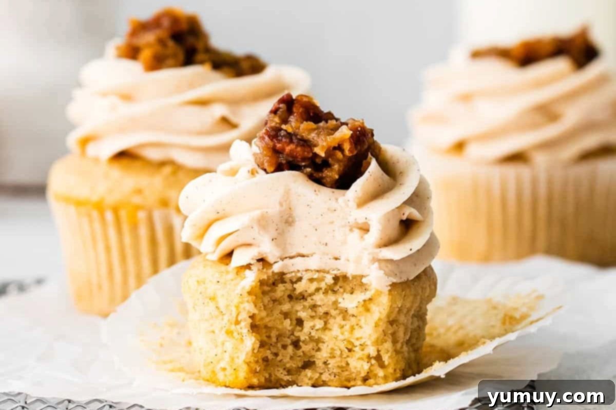 An unwrapped and bitten pecan pie cupcake on a wire rack, revealing its soft interior and filling.