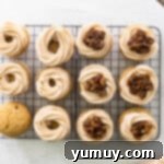 Showing how to frost pecan pie cupcakes with a frosting ring around the top of each cupcake and pecan pie filling in the center
