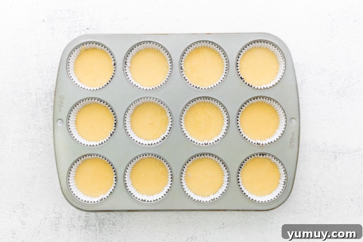 Cannoli Dream Cupcakes 11 Cupcake batter carefully poured into lined muffin tin wells, ready for baking.
