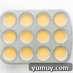 Cannoli Dream Cupcakes 6 Cupcake batter being divided into a lined muffin tin for baking cannoli cupcakes.