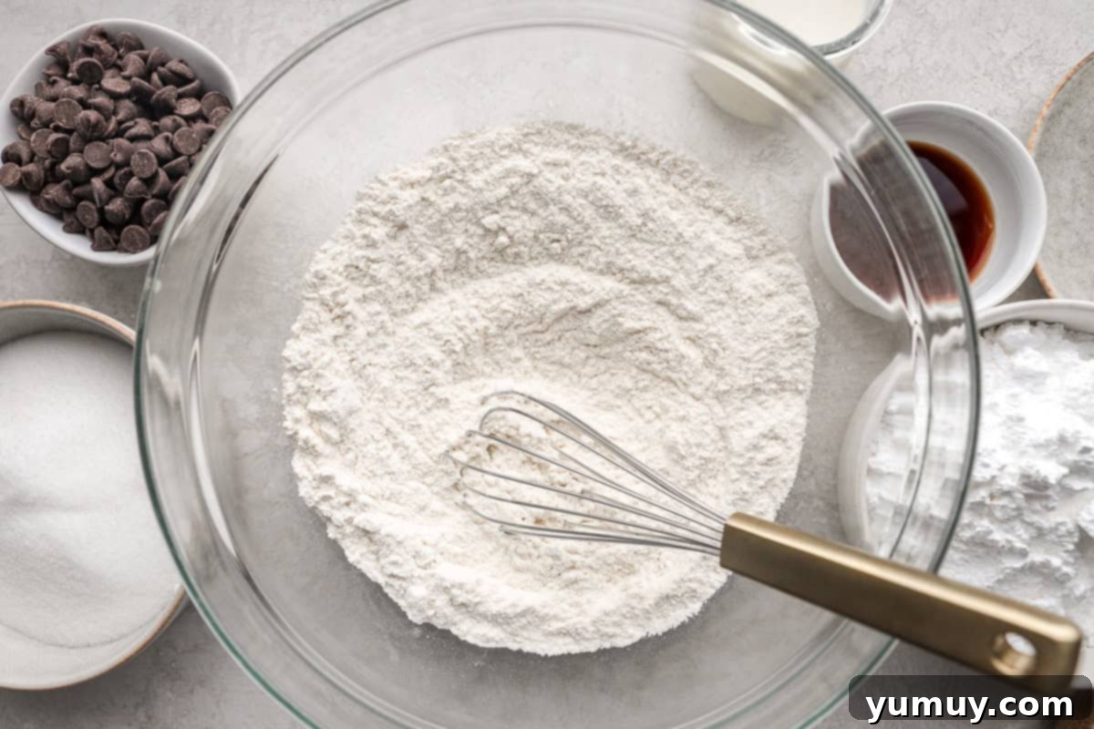 Ultimate Chocolate Chip Cupcakes 6 A large mixing bowl containing perfectly blended dry ingredients for cupcakes, with a whisk resting inside, ready for the next step.
