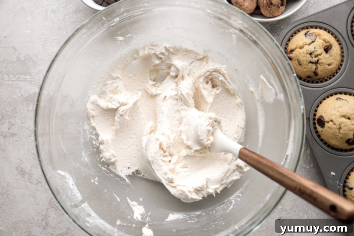 Ultimate Chocolate Chip Cupcakes 13 Decadent vanilla buttercream frosting, perfectly smooth and creamy, showcased within a clear glass mixing bowl, ready for piping.