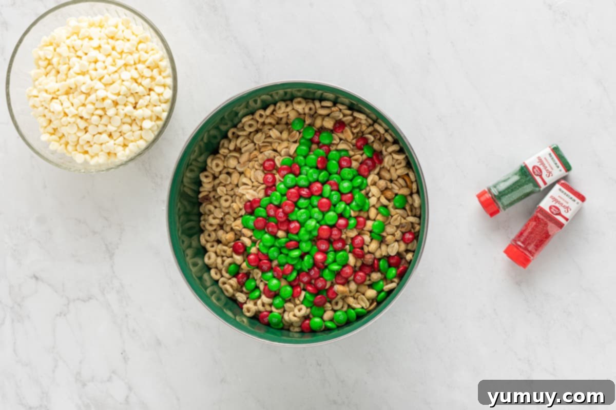 Dry ingredients for Christmas Crack Chex Mix combined in a large bowl, including cereals, pretzels, peanuts, and M&M's.