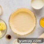pie dough placed into a glass pie dish with ingredients in bowls