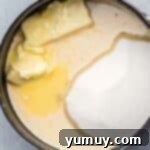 Butterfinger Bliss Fudge 5 Melting butter, sugar, and evaporated milk in a saucepan for fudge base