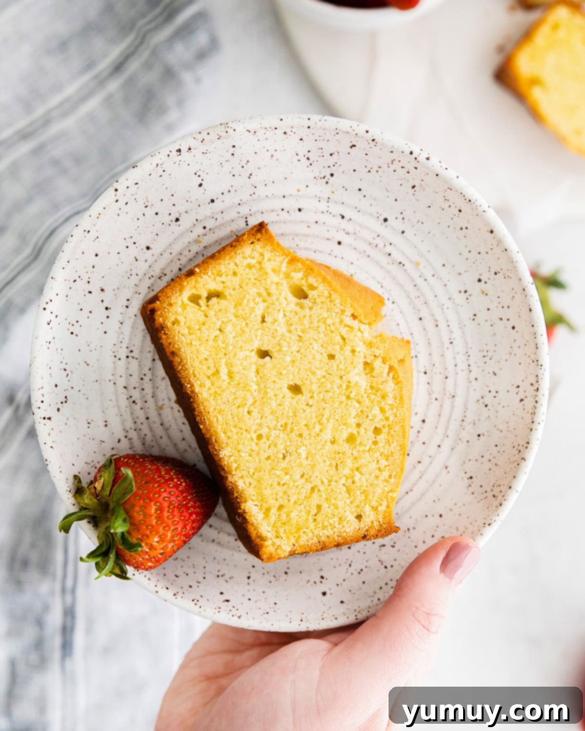 Classic Vanilla Pound Cake 2 overhead view of a slice of vanilla pound cake on a white plate with a strawberry.