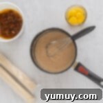 Velvet Raisin Bliss 9 Custard mixture simmering in a saucepan while being whisked.