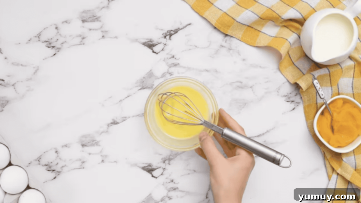 egg wash in a glass bowl with a whisk.