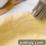 brushing egg wash on pie crust.