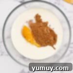 pumpkin puree and other wet ingredients being whisked in a bowl.