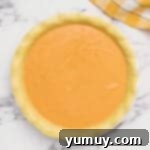 pumpkin pie filling in a pie crust before baking.