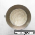 Freshly whipped cream with maple syrup and vanilla extract in a metal bowl, forming stiff peaks for the pumpkin mousse.