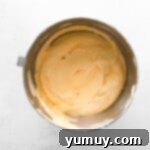Pumpkin mousse mixture with gently folded whipped cream in a large metal bowl, showing its light and airy texture.