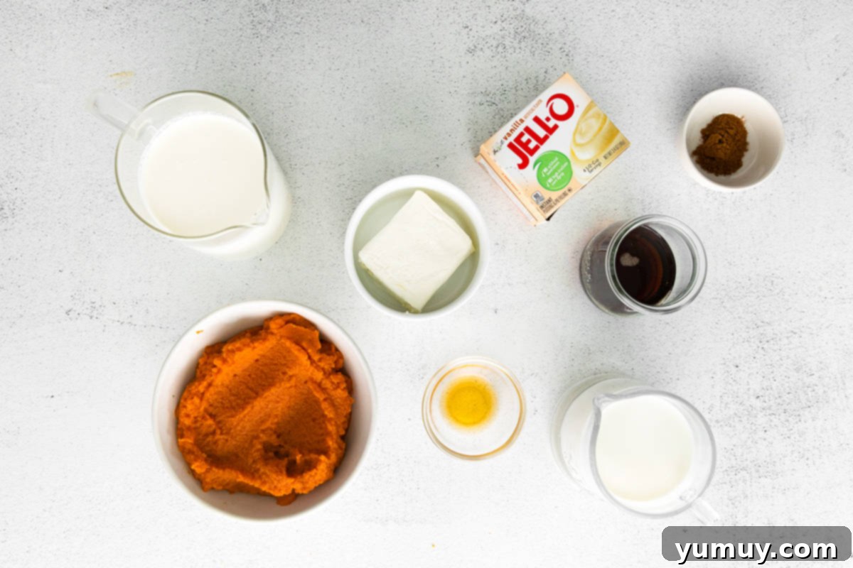 A selection of fresh ingredients including pumpkin puree, cream cheese, heavy cream, maple syrup, and spices laid out on a kitchen counter, ready for making pumpkin mousse.