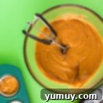 pumpkin cupcake batter in a glass bowl with a cookie scoop