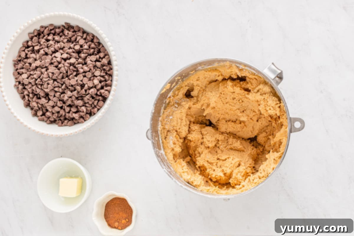 Creamy peanut butter confection being mixed vigorously in a stainless steel mixing bowl.