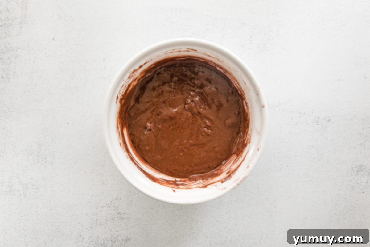 Smooth and rich chocolate pumpkin cupcake batter in a white bowl, freshly mixed and perfectly combined, ready for portioning.