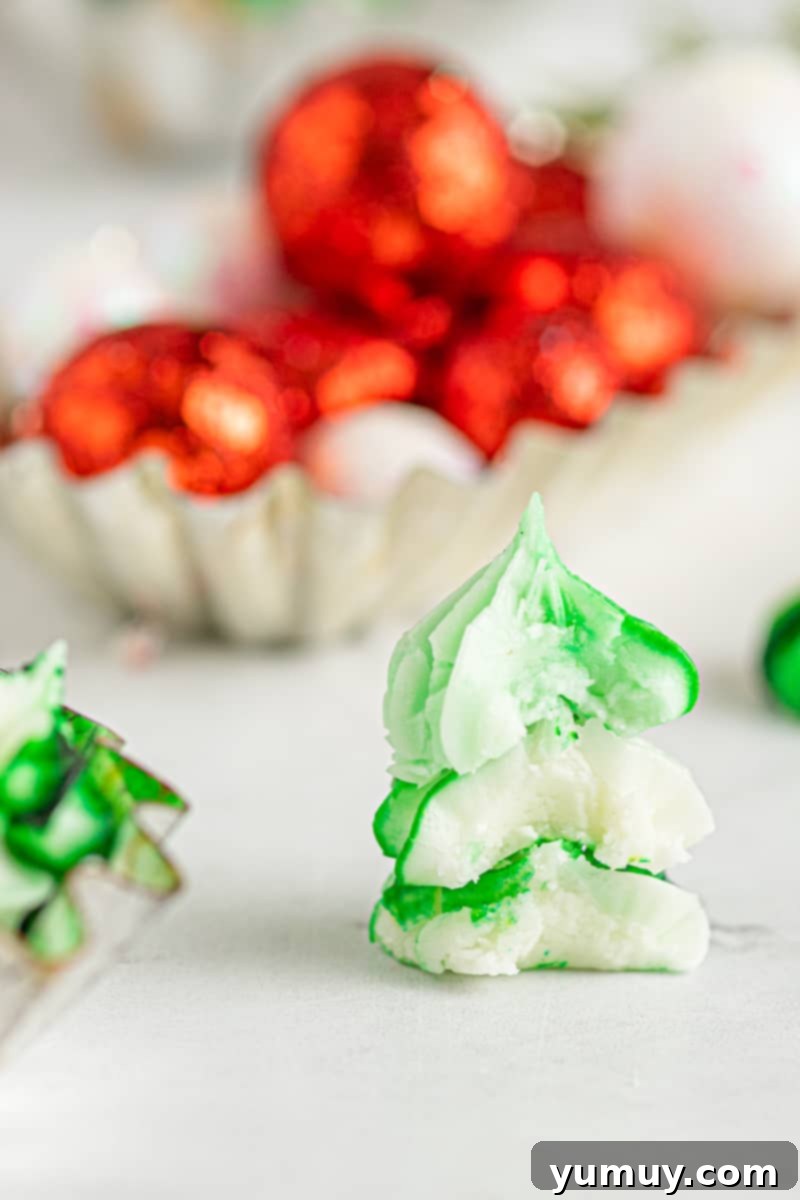 A delightful stack of green and white cream cheese mints, with a few showing small bites taken, highlighting their soft, chewy texture.