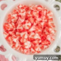Festive red and white swirled cream cheese mints artfully arranged in a white bowl, perfect for Christmas.