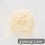 Ball of uncolored bread dough in a stand mixer bowl