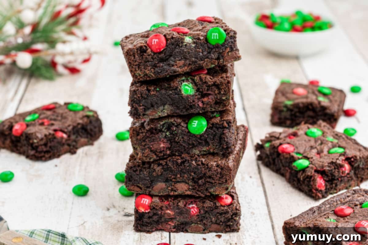 A stack of delicious Christmas M&M brownies, showcasing their thick, fudgy texture and the colorful candies embedded within.