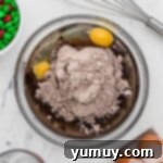 Brownie batter being mixed in a clear glass bowl, showcasing its rich, dark texture.