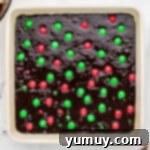 Unbaked brownies with Christmas M&M's in a white baking dish, ready for the oven.