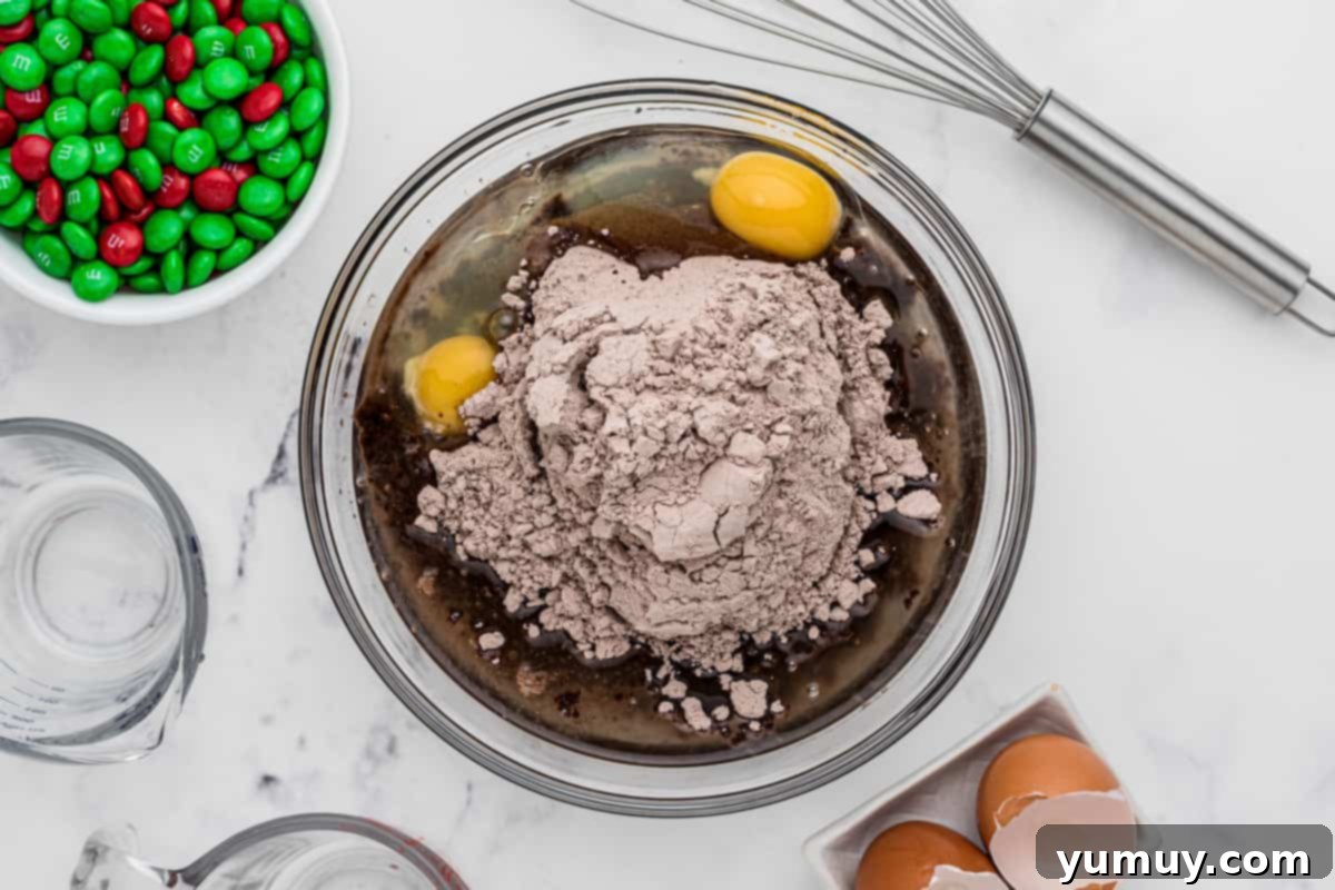 Brownie batter being stirred in a glass mixing bowl, creating a smooth, chocolatey consistency.