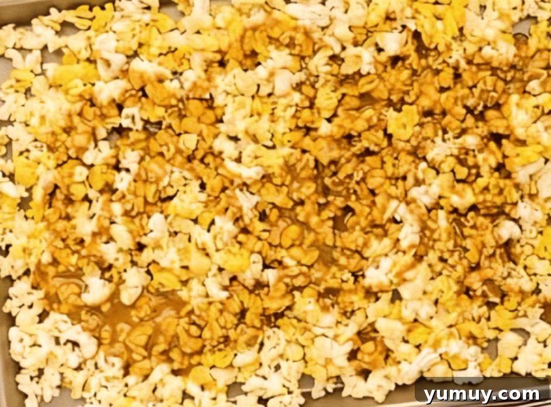 Golden Caramel Crunch 14 caramel poured over popcorn on a baking sheet.