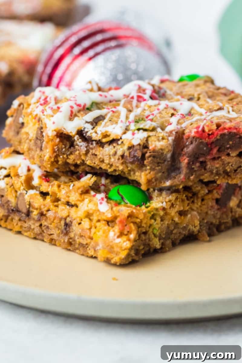 2 christmas 7 layer magic cookie bars on a white plate with a bite taken from one
