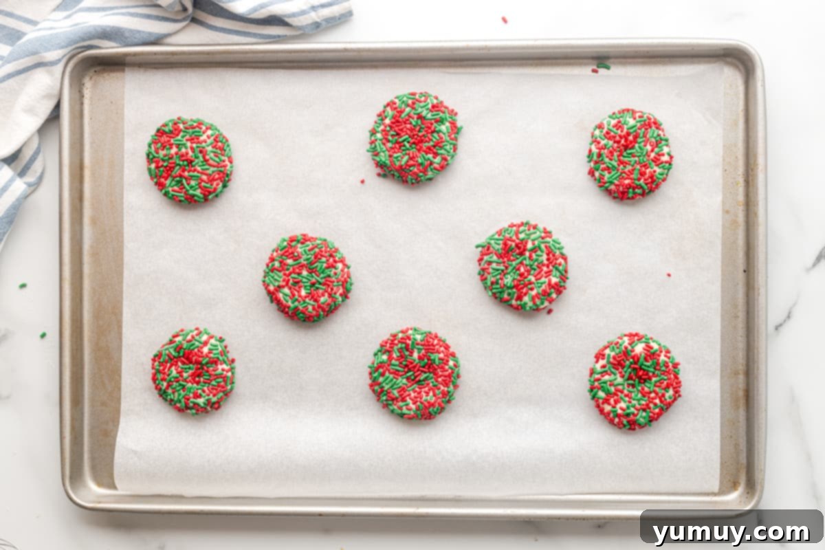 sugar cookies with red and green sprinkles on a baking sheet before baking