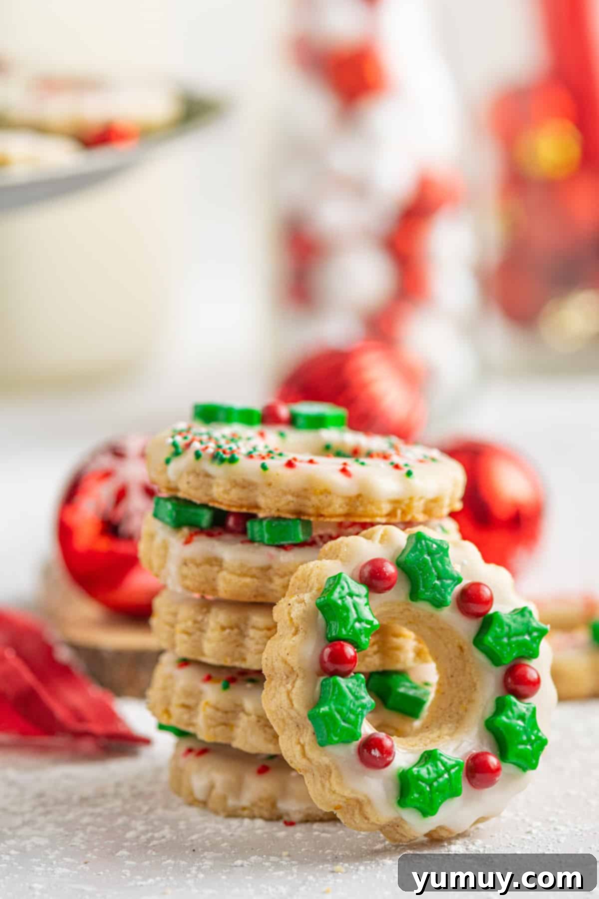 Holiday Wreath Delights 2 A beautifully arranged stack of shortbread wreath cookies, showcasing their intricate Christmas decorations and inviting glaze.