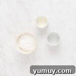 Festive Gingerbread Treats 15 Ingredients for royal icing – powdered sugar, milk, and corn syrup – separated in small bowls.