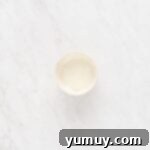 Festive Gingerbread Treats 16 Smooth white royal icing in a small white bowl, ready to be transferred to a piping bag.